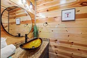 This full bathroom offers modern comfort with fresh towels, toilet paper, hand soap, body soap, and a hair dryer. Featuring a walk-in shower, granite vanity, and cozy cabin charm, it's stocked with essentials to ensure a refreshing & hassle-free stay